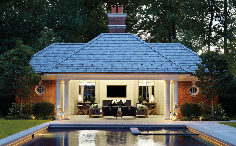 The pool house lit up at night, its pillars reflected in the large mirrors and the water. The lanterns are from Restoration Hardware.