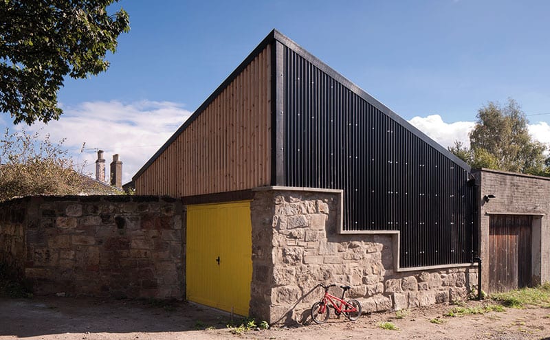 Black corrugated cladding from Cladco combines effectively with the original reclaimed stone of the old stables and the strips of larch. The pyramid shape was chosen as it gives the most space without overshadowing the neighbours.
