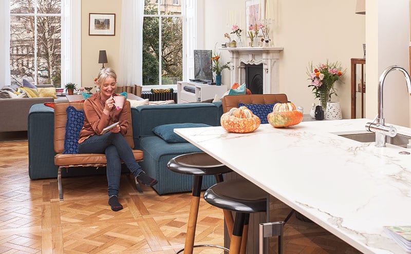 A pair of toffee-coloured leather chairs from Galletly & Tubbs contrast with the kingfisher velvet modular BoConcept sofa in the open-plan living room