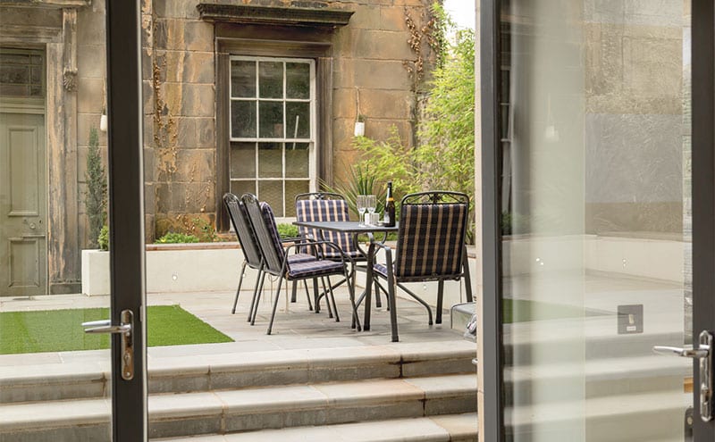 Pale sandstone slabs help the garden to feel light and bright, while the artificial lawn keeps maintenance to a minimum