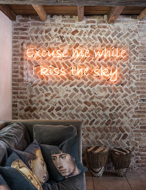 McNeill enjoys juxtaposing old and new. Here, medieval herringbone pattern brickwork is visible behind a Perspex panel which displays a neon quote from Jimmy Hendrix’s ‘Purple Haze’. The portrait cushions on the sofa were printed for McNeill by Digitex