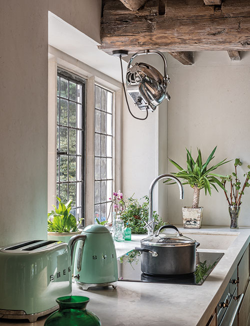 A vintage 1930s film light fixed to a beam illuminates the working area in the kitchen