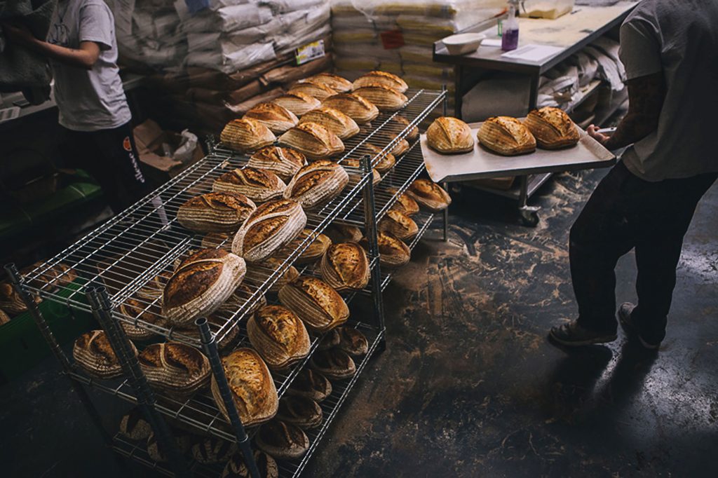 Dozens-of-sourdoughs-fresh-out-of-the-oven-cool-on-wire-racks-before-being-loaded-into-the-van-for-delivery