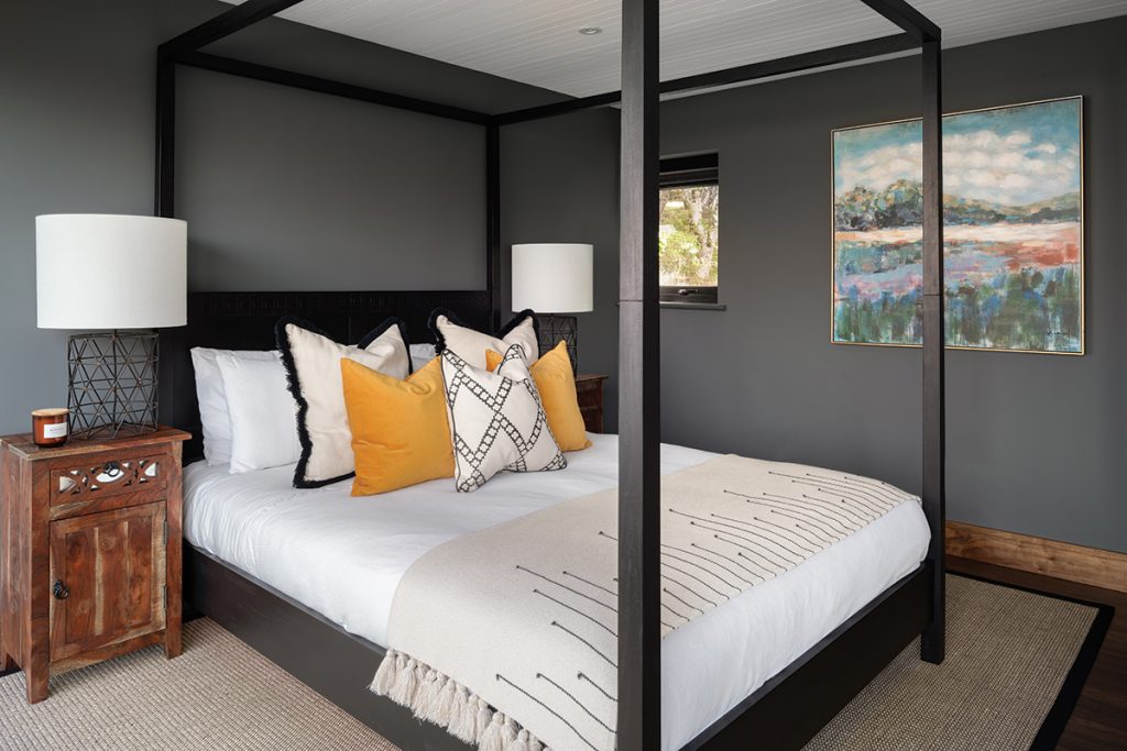 four-poster-bed-with-orange-cushion-and-white-linen
