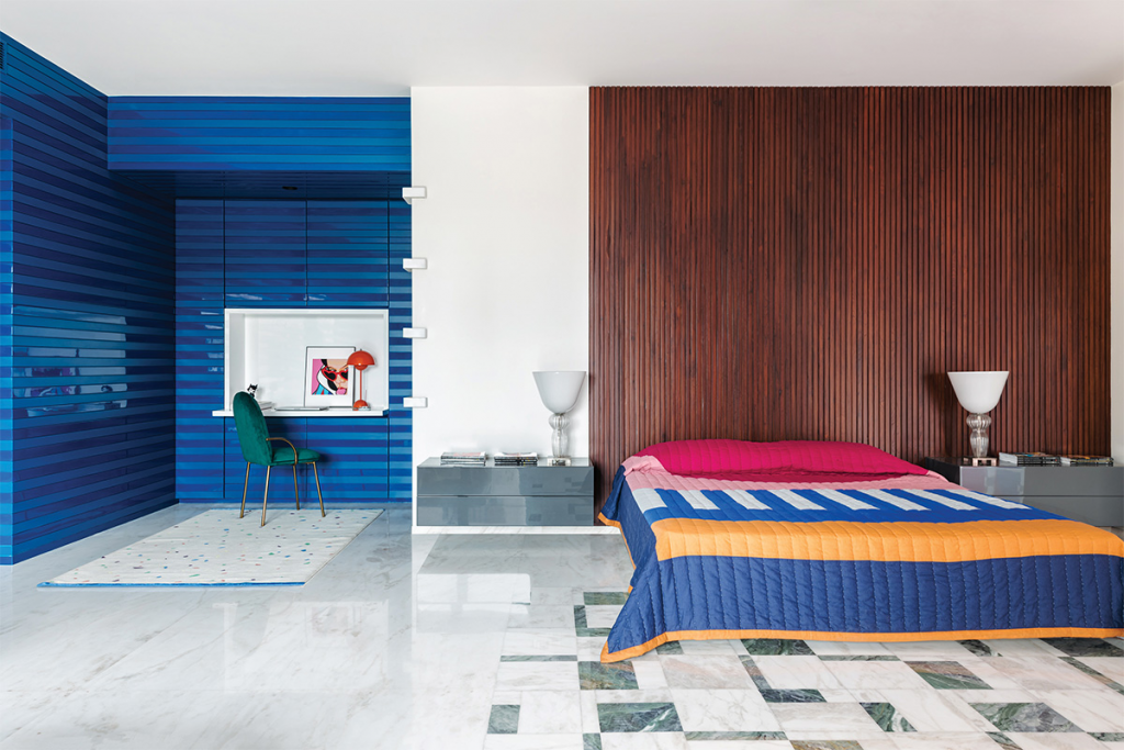 bold interior, blue cladding on the wall and a graphic bedspread on the right hand bed