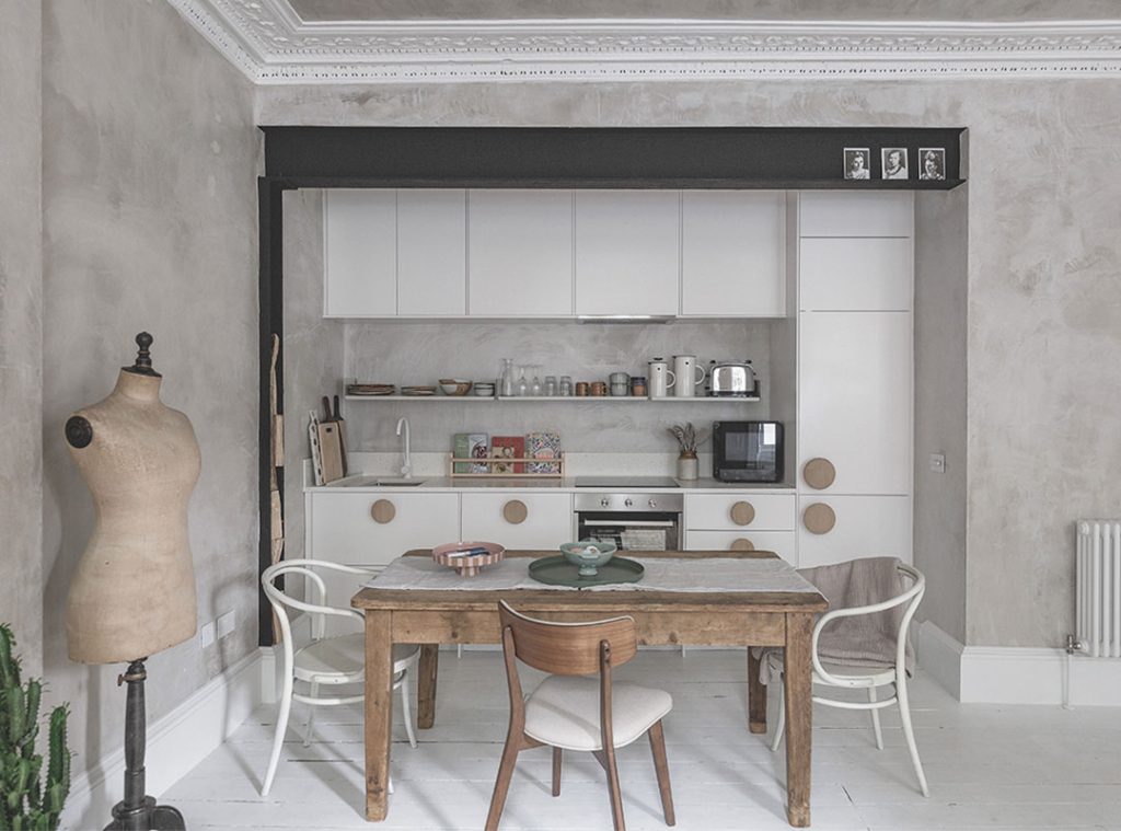 The open plan kitchen with white cabinets and a distressed wooden dining table. Stockbridge Edinburgh staycation