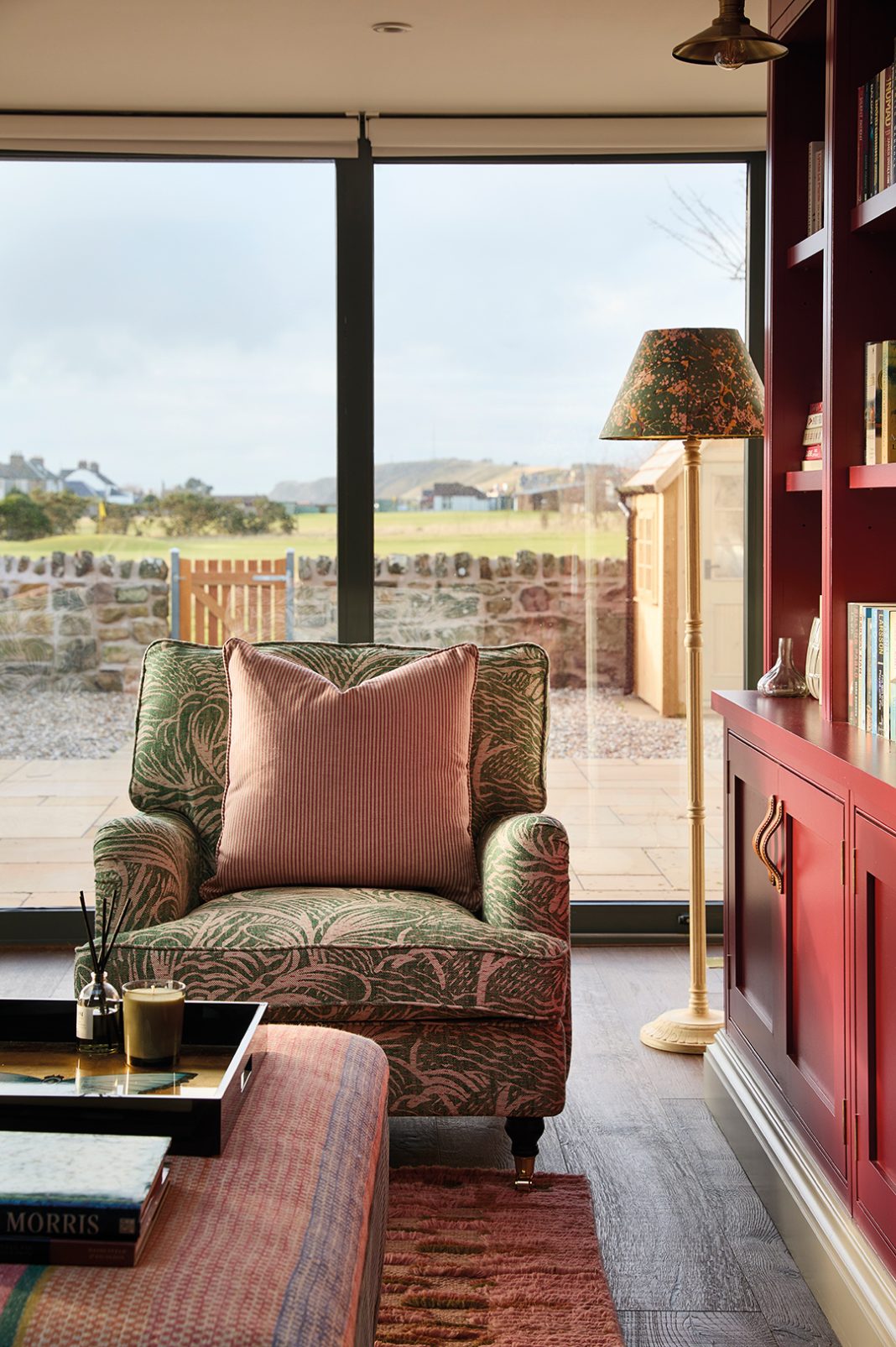 view from sitting area out to sea. Comfy armchair, floor standing lamp, colourful cabinetry