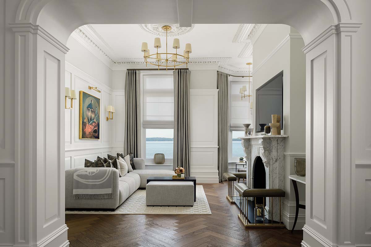 living room with large window, fireplace with fenders and neutral furniture 