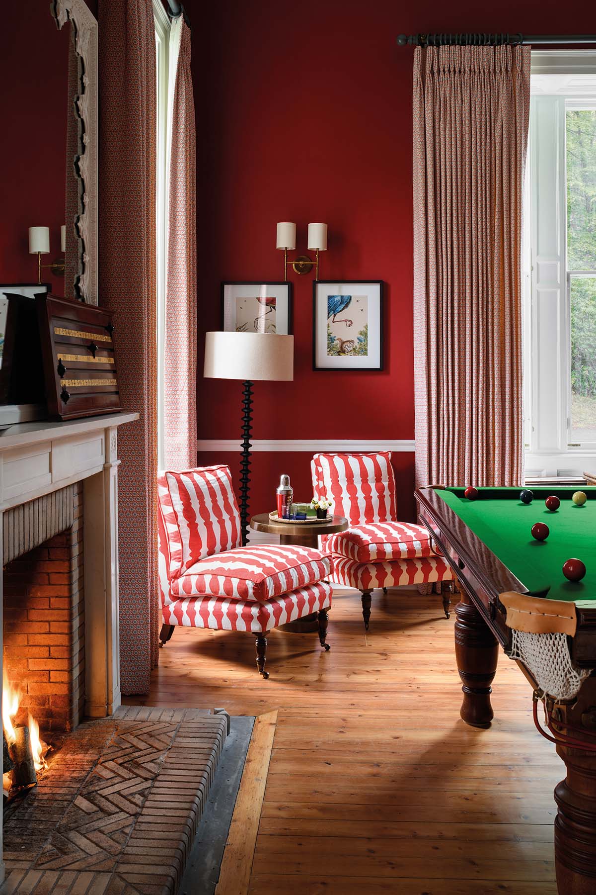 billiard room with two red slipper chairs and fireplace