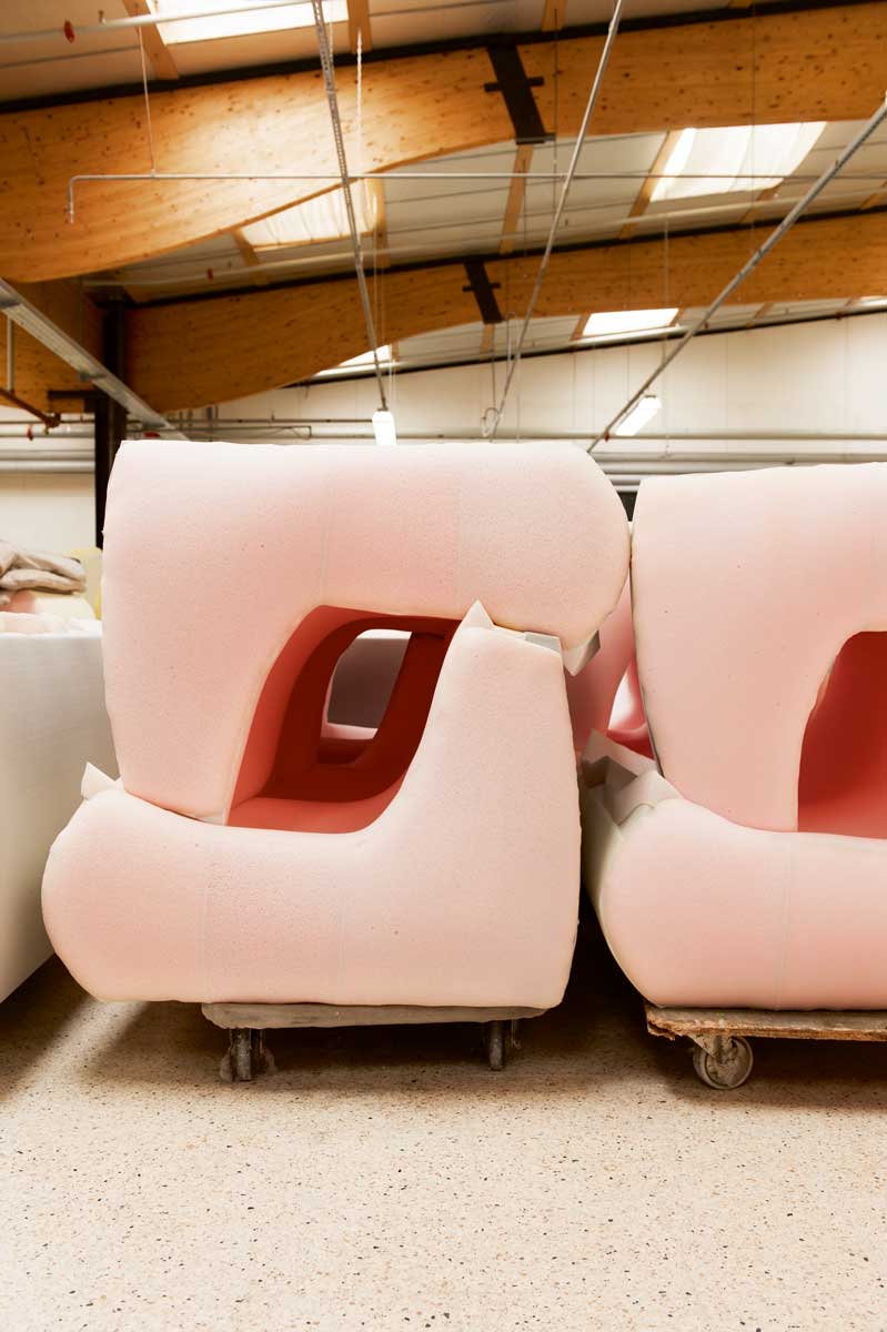 Pink and red Togo sofas are Tetris stacked on top of each other in the factory