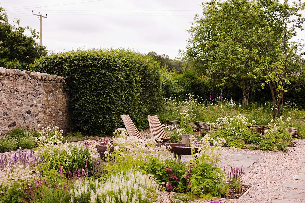 a beautiful garden space with chairs and a fire pit