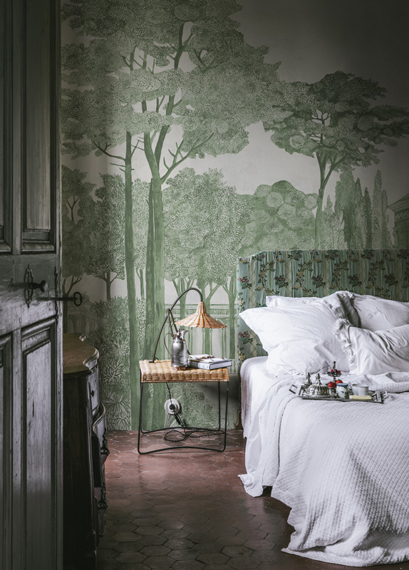 Chatsworth Park in Green by Rebel Walls elaborate wallpaper with green forest illustration behind a double bed with crisp white sheets