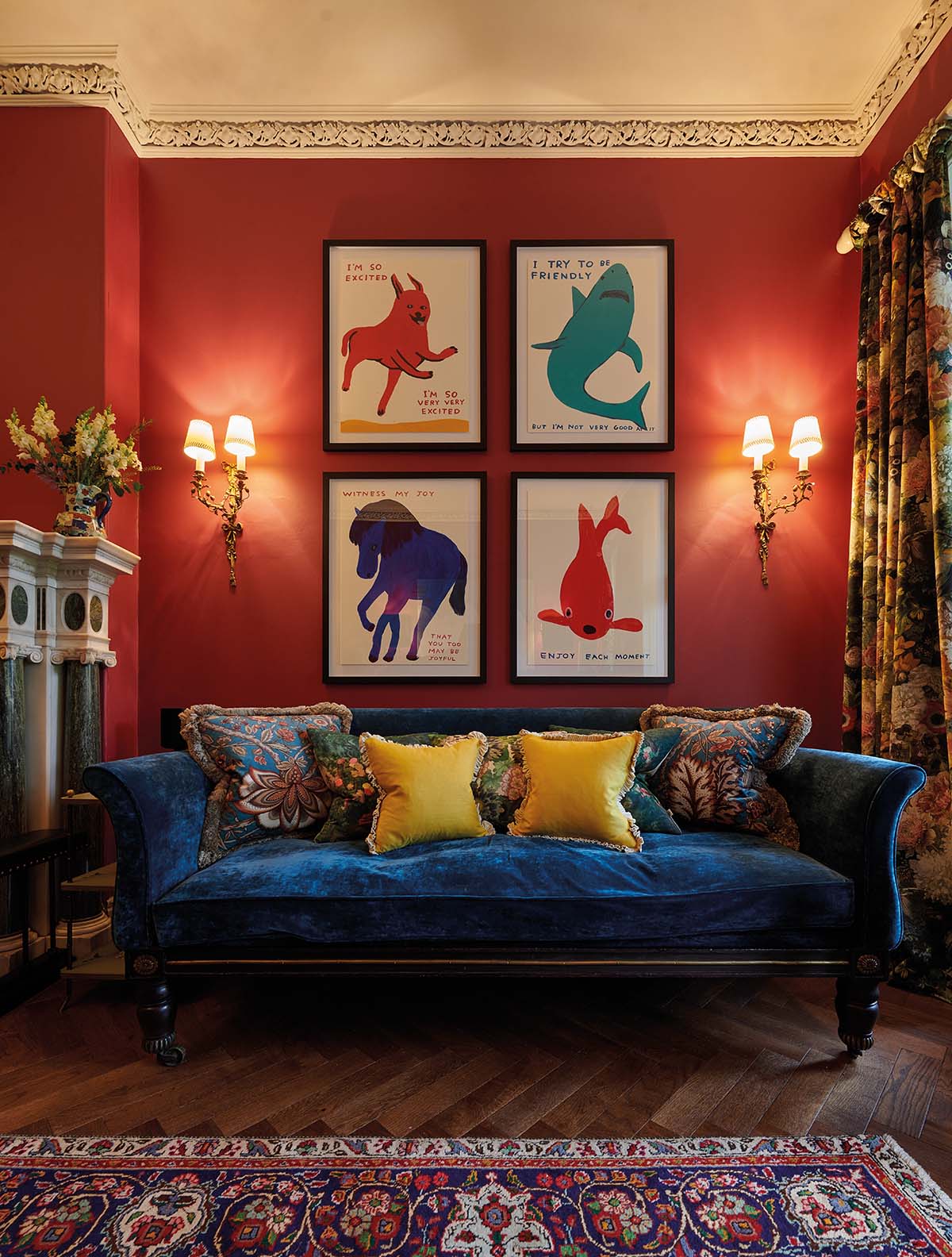 A seating area with a gallery wall which is painted red and a blue sofa
