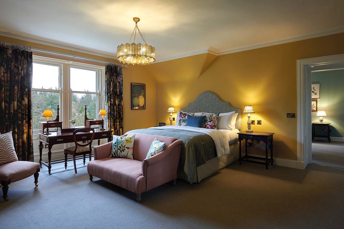 A large bedroom suite, with walls painted yellow and a view of trees