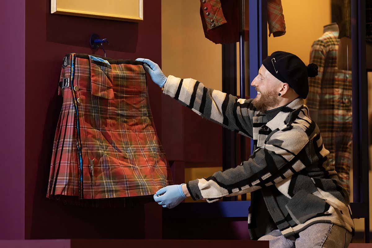 A man arranges Billy Connolly's kilt to for display at V&A Dundee