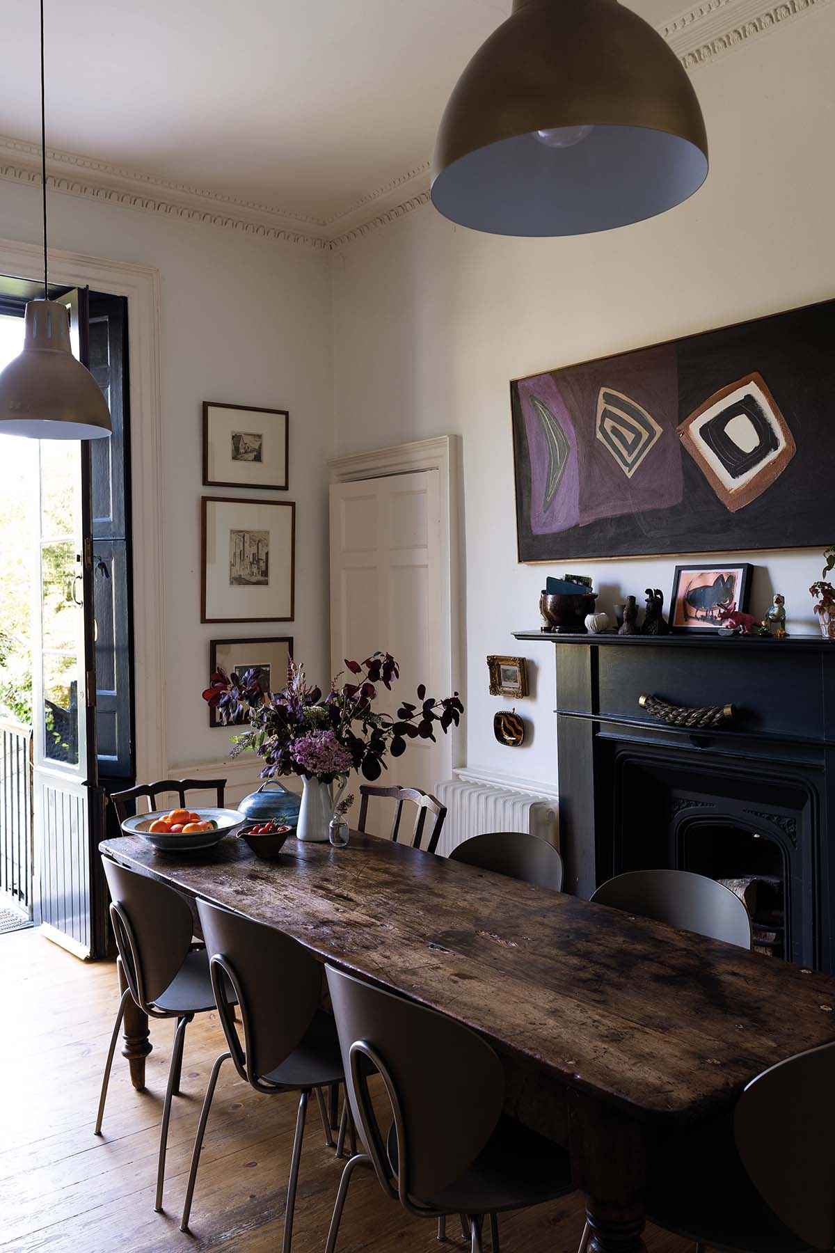 A dining area with wooden table, brown chairs, a fireplace in the background and purple accents, including a piece of artwork on the wall in shades of purple