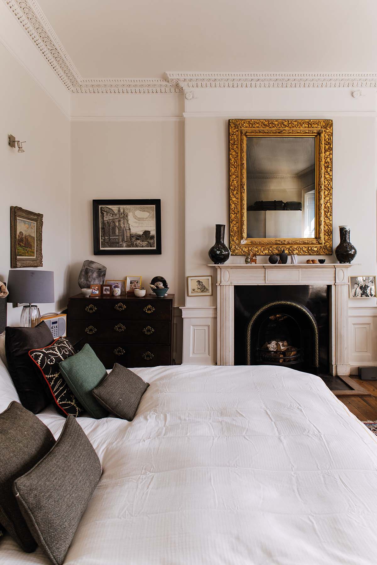 A bedroom with a large bed, fireplace and art on the walls