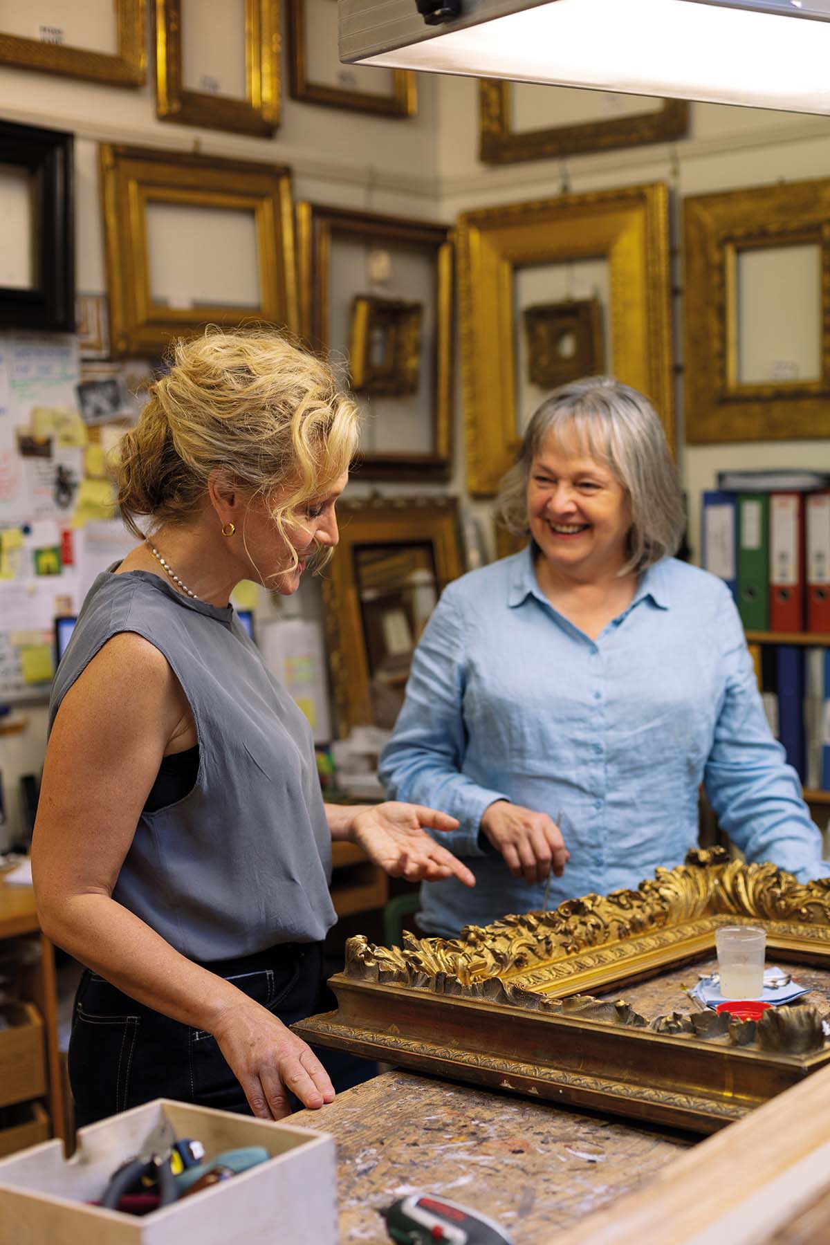 Two women stand in a framing workshop