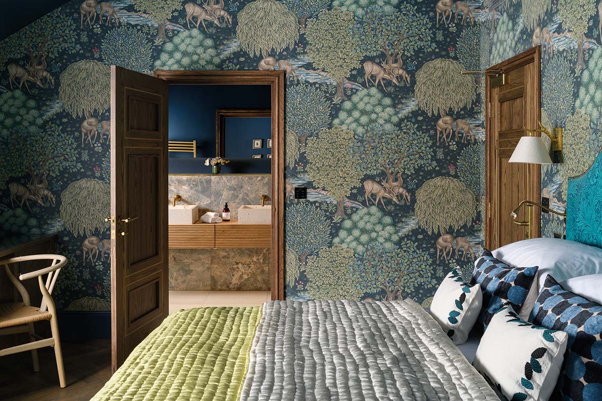 Bedroom with floral wallpaper and door open to ensuite bathroom at new hotel
