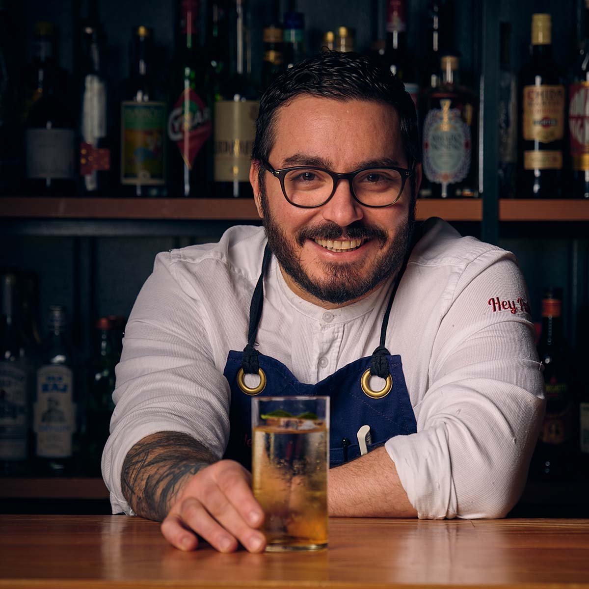 a portrait of a bartender, leaning on a bar