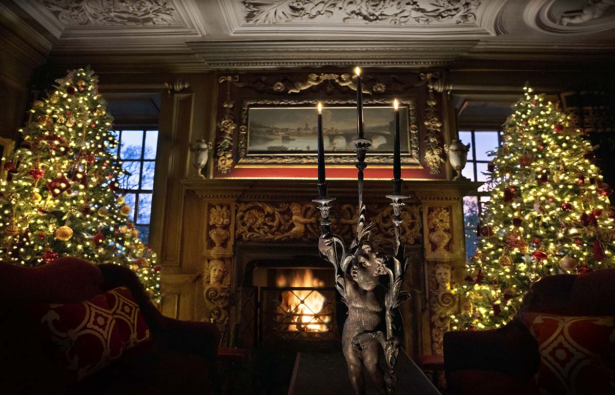 a fireplace and two Christmas trees in Prestonfield House