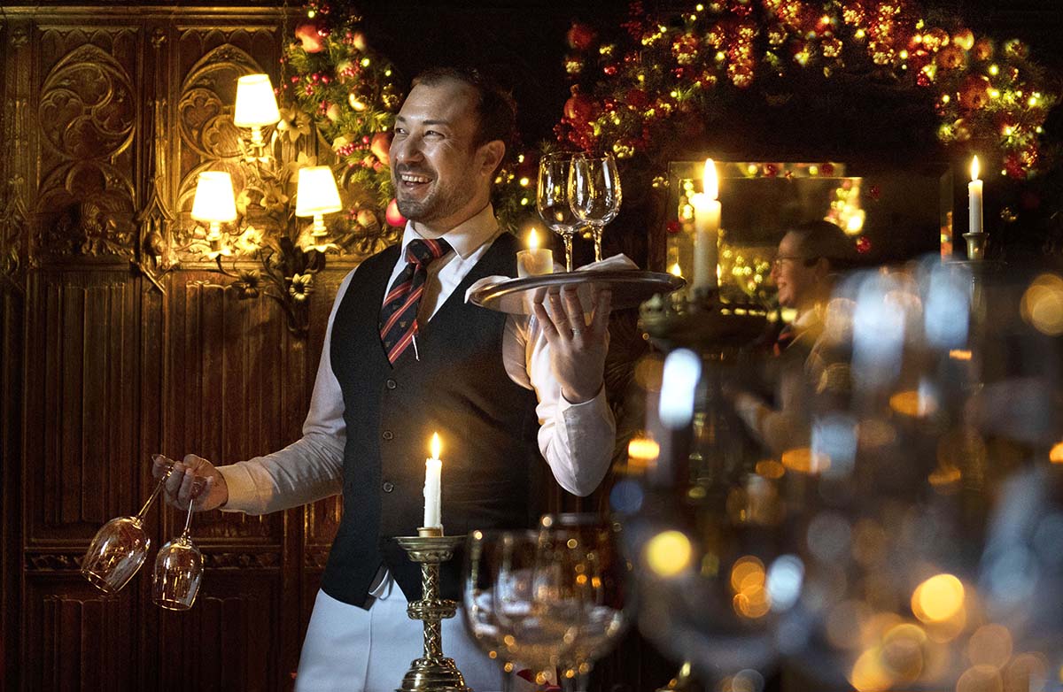 A waiter carrying wine glasses in a Christmas set up at The Withery