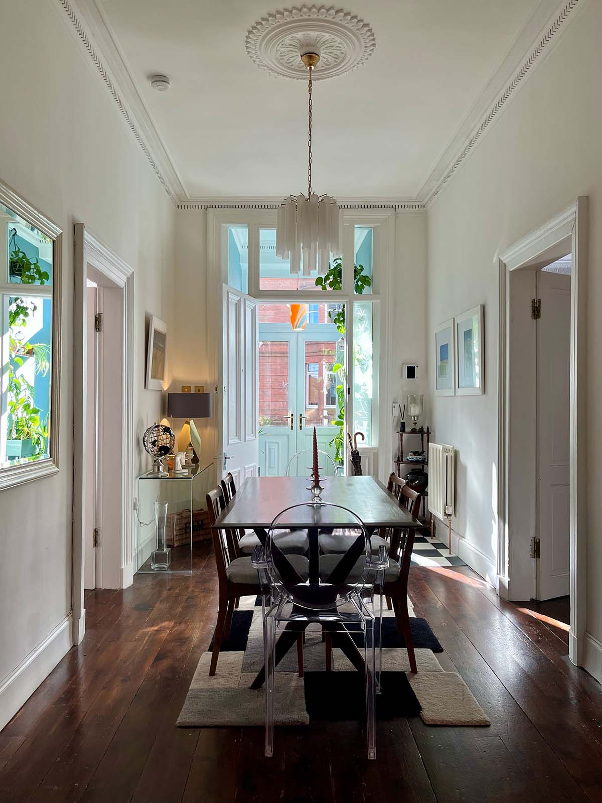 a hallway with a chandelier and a dining table