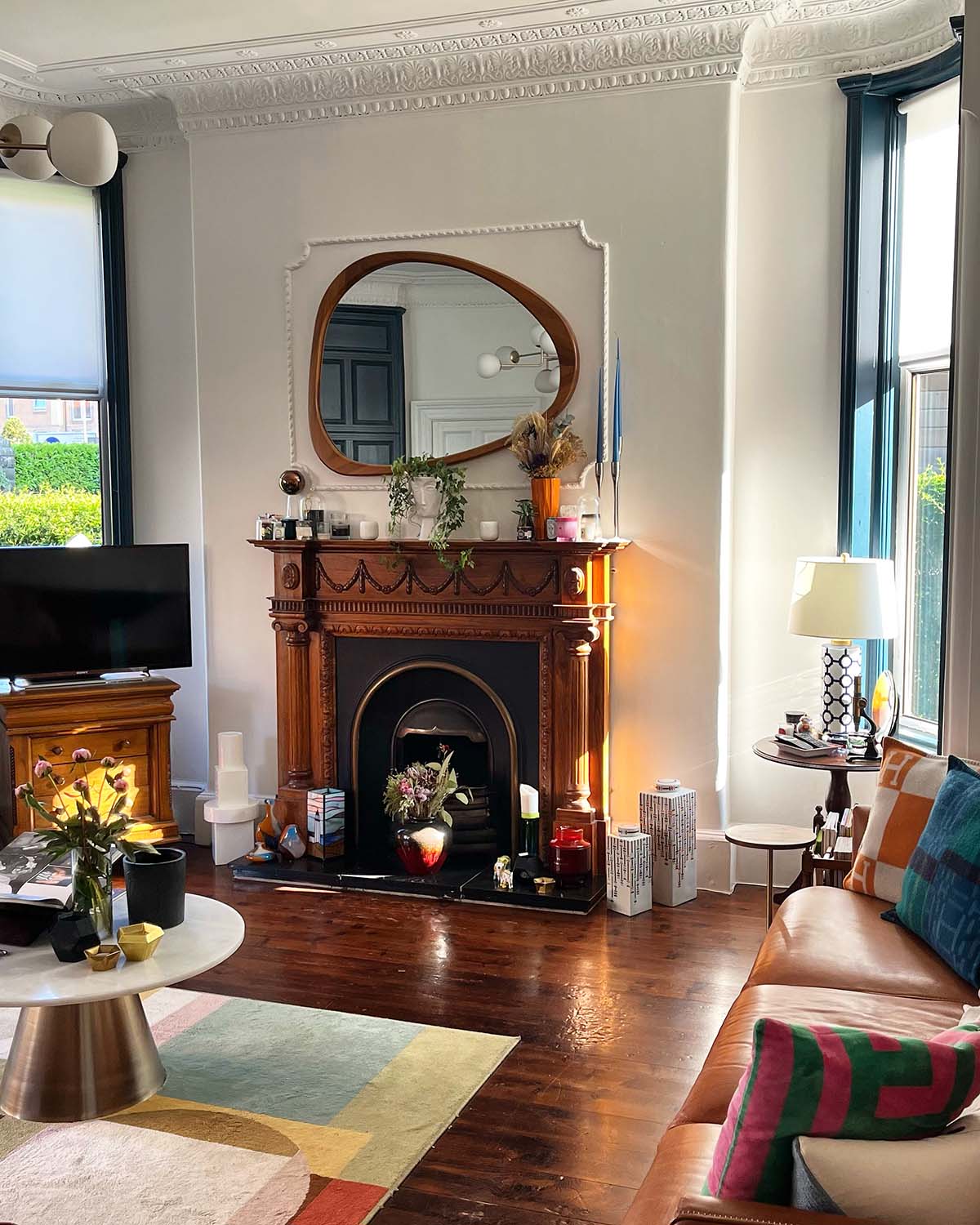 a living room in a tenement flat with a wooden panelled fireplace and statement mirror above the mantelpiece