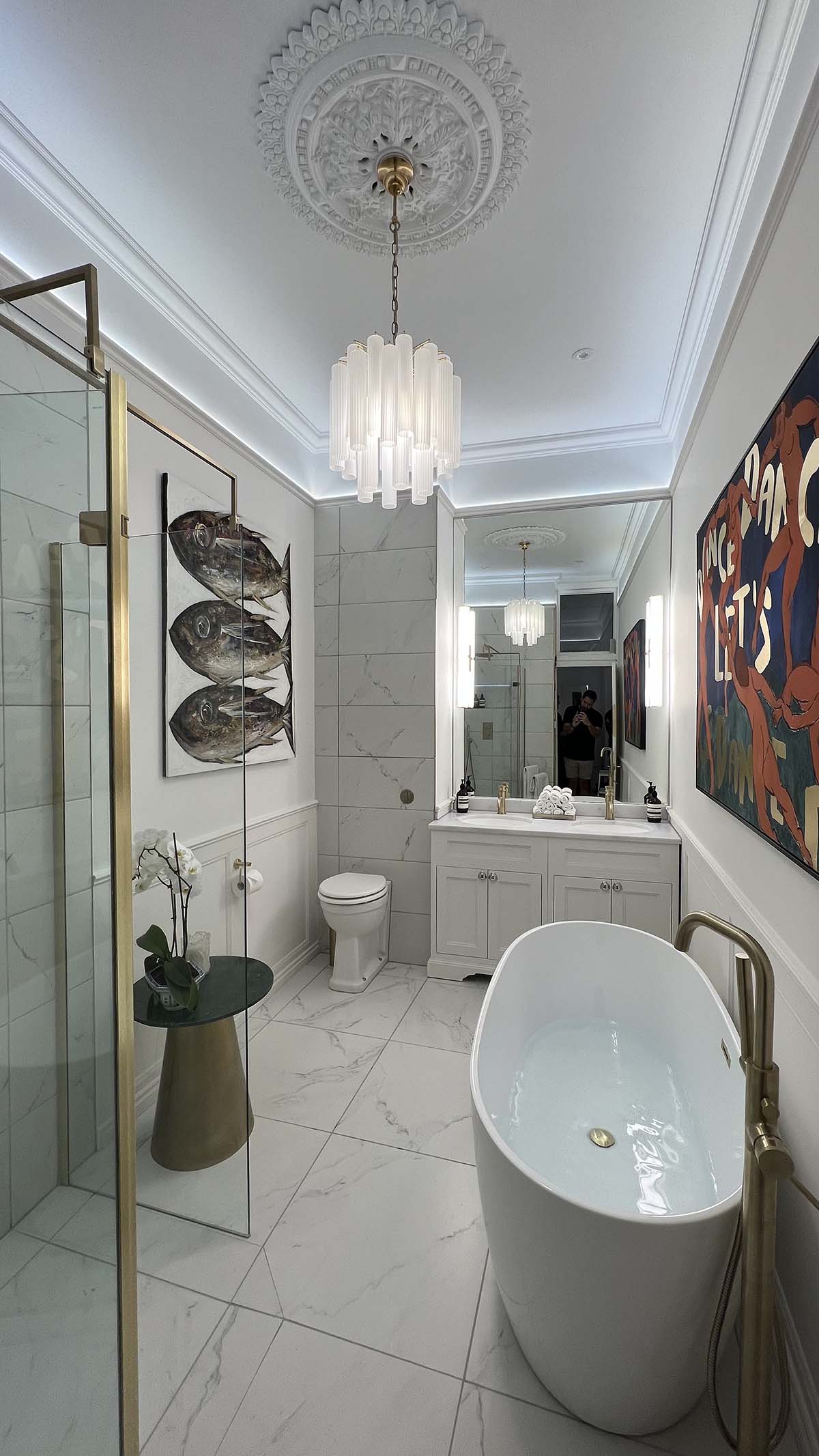 A bathroom with standalone bath, double sinks, chandelier and white marble countertop