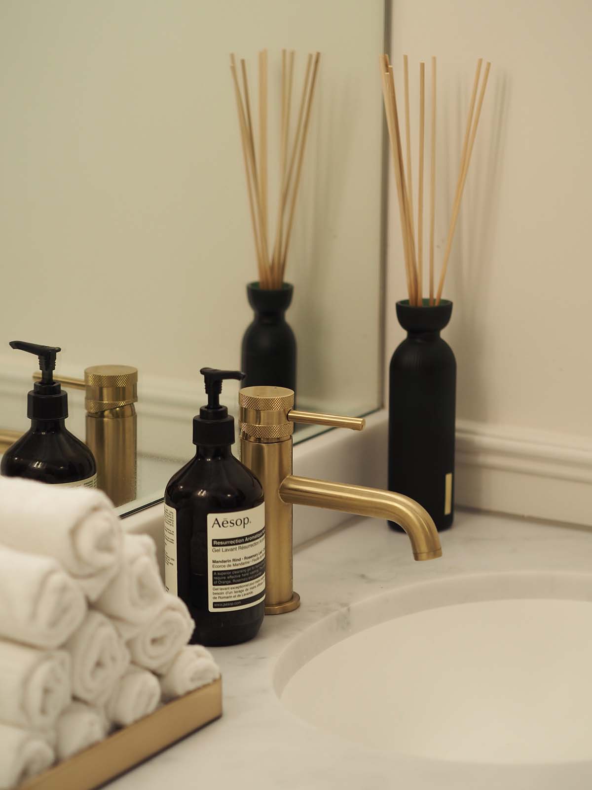 Details of items on a sink, including face cloths and Aesop soap