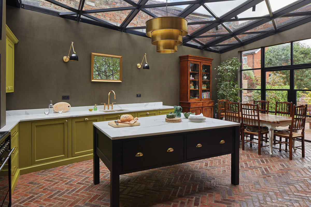 A kitchen with a glass roof and vibrant lime cabinetry, a free standing island and a dining table
