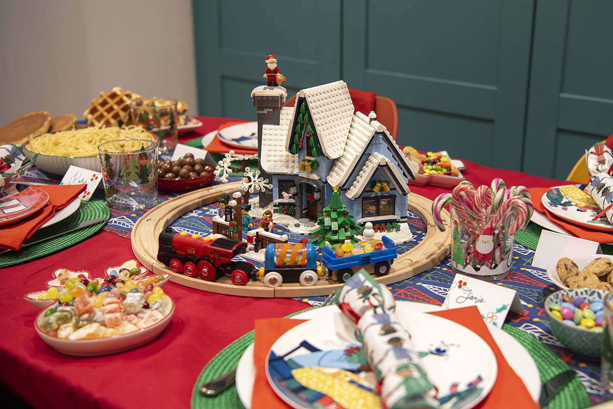 a festive tablescape, with a model train, crackers and other decorations