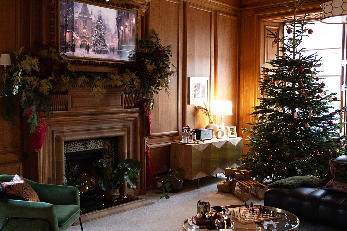 a wood panelled room with a Christmas tree and festive foliage on the mantle piece