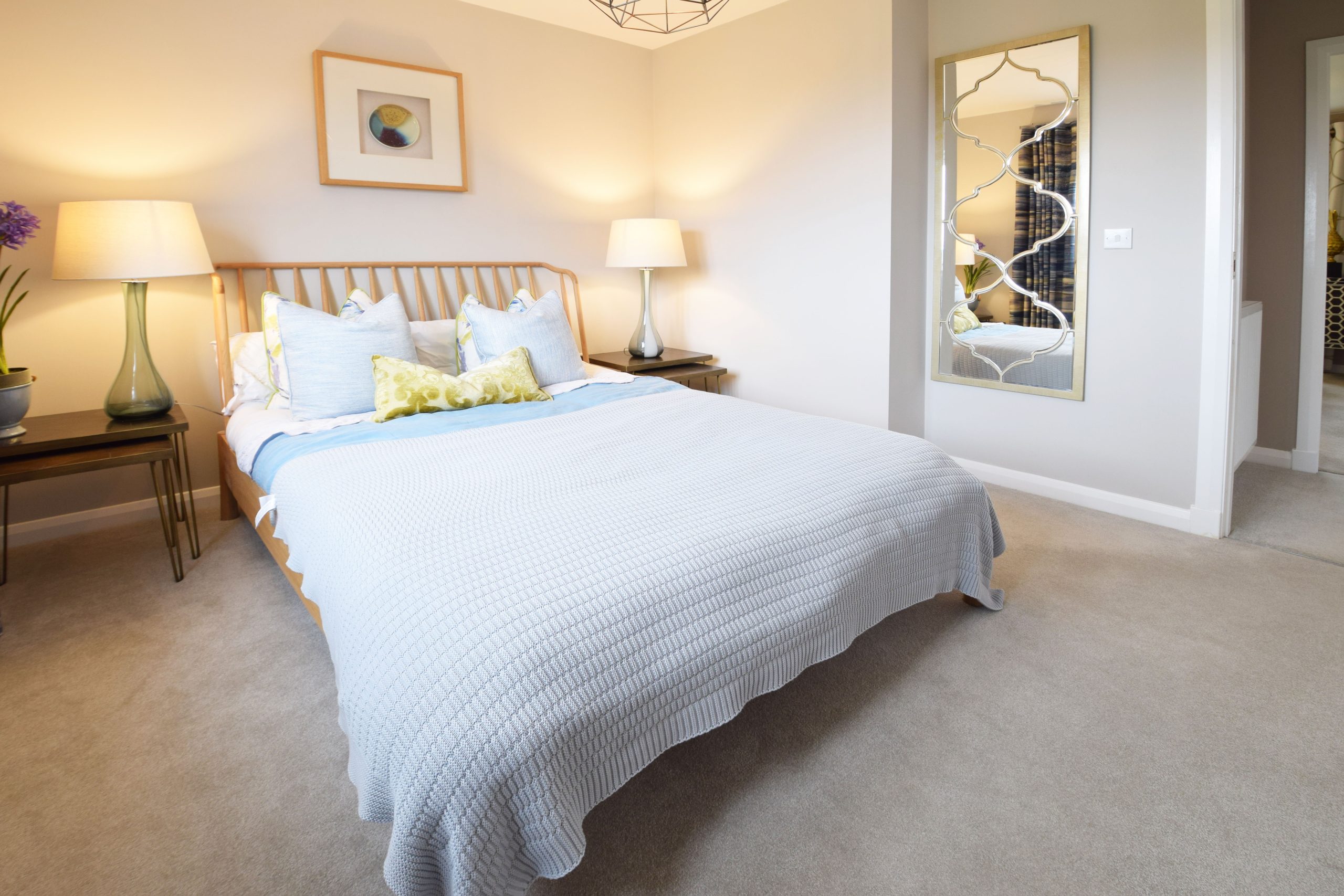 a bedroom with double bead, grey carpet and neutral walls