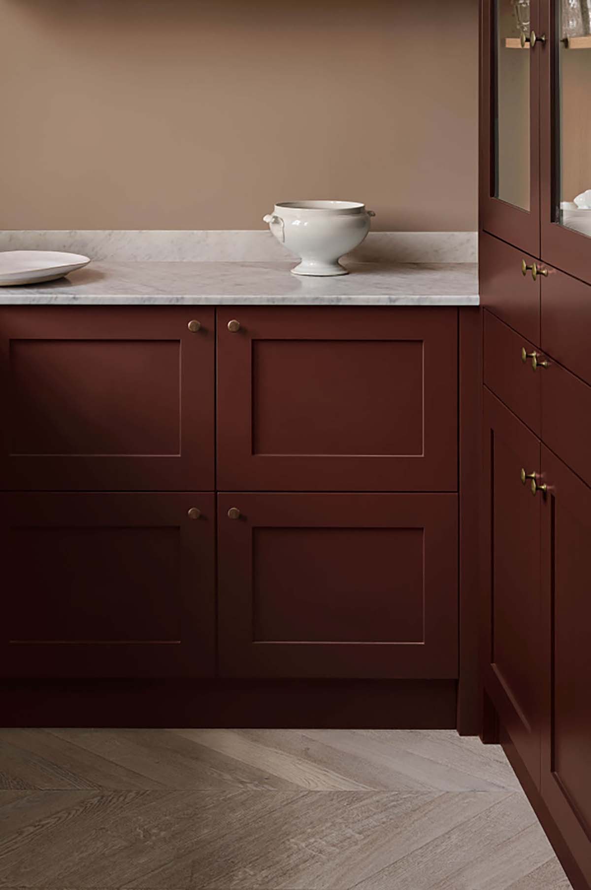 A kitchen with cabinets painted a deep red brown shade, marble counter tops and mink walls