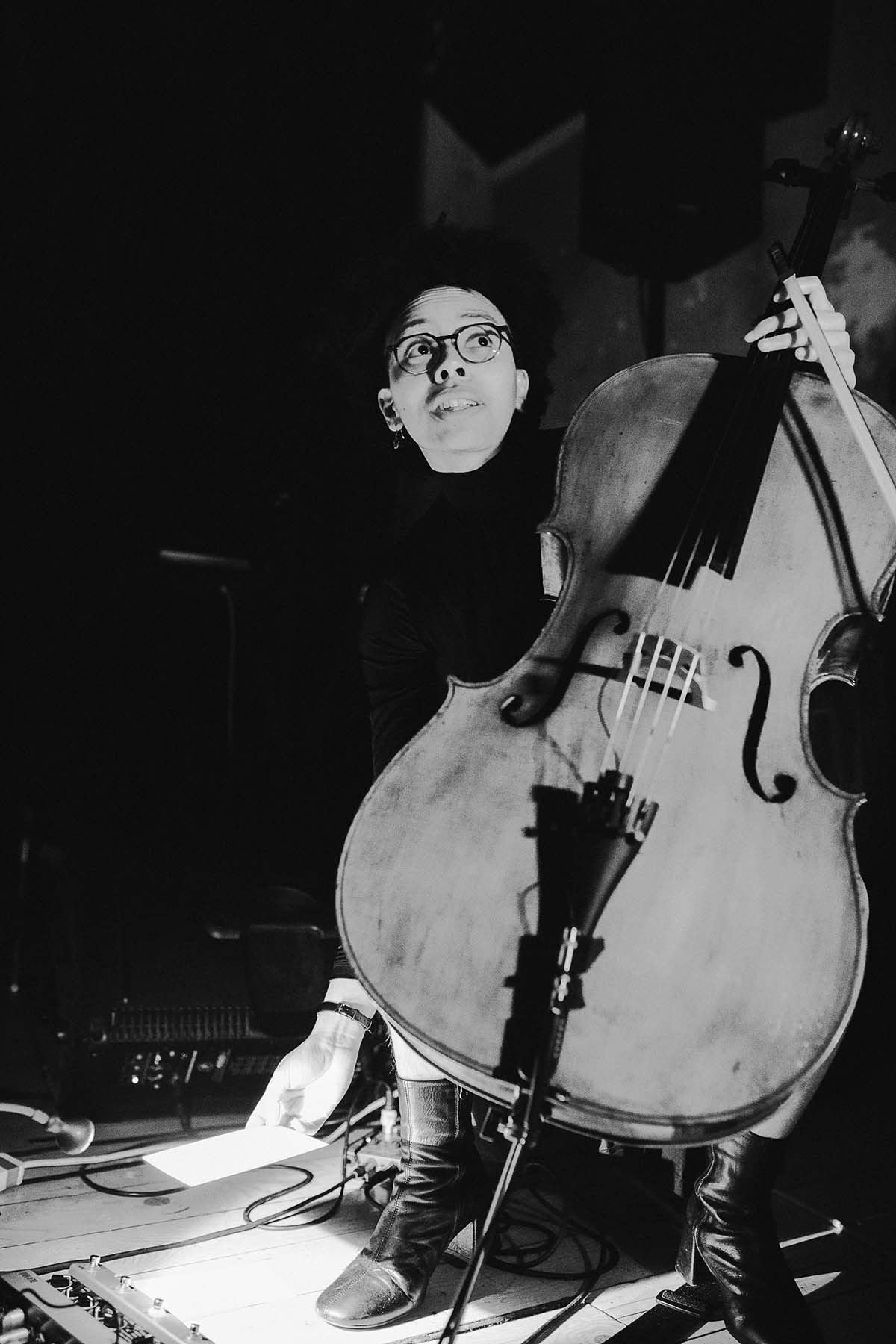 a black and white image of a cellist on stage