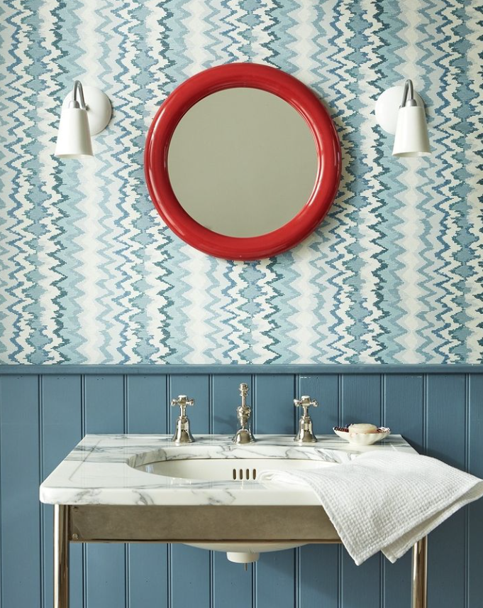 An example of unexpected red theory in a blue bathroom with a bold red mirror