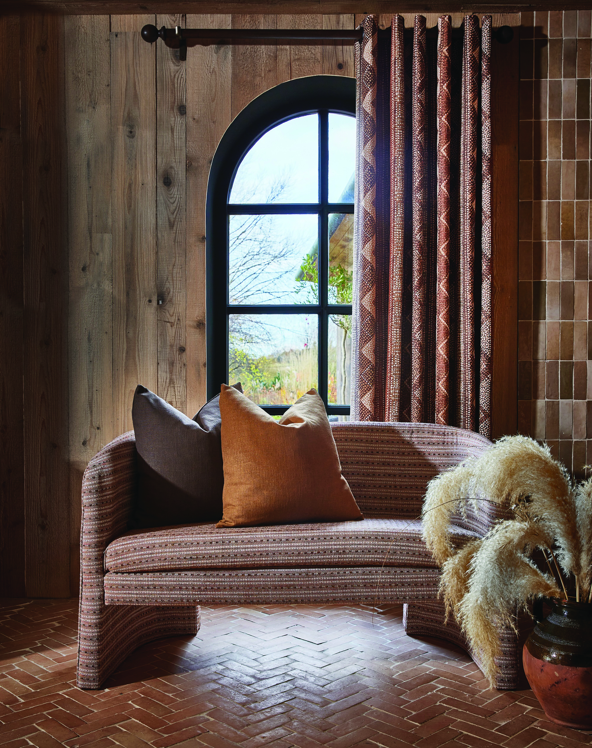 A living room in brown and orange tones with curtains and sofa