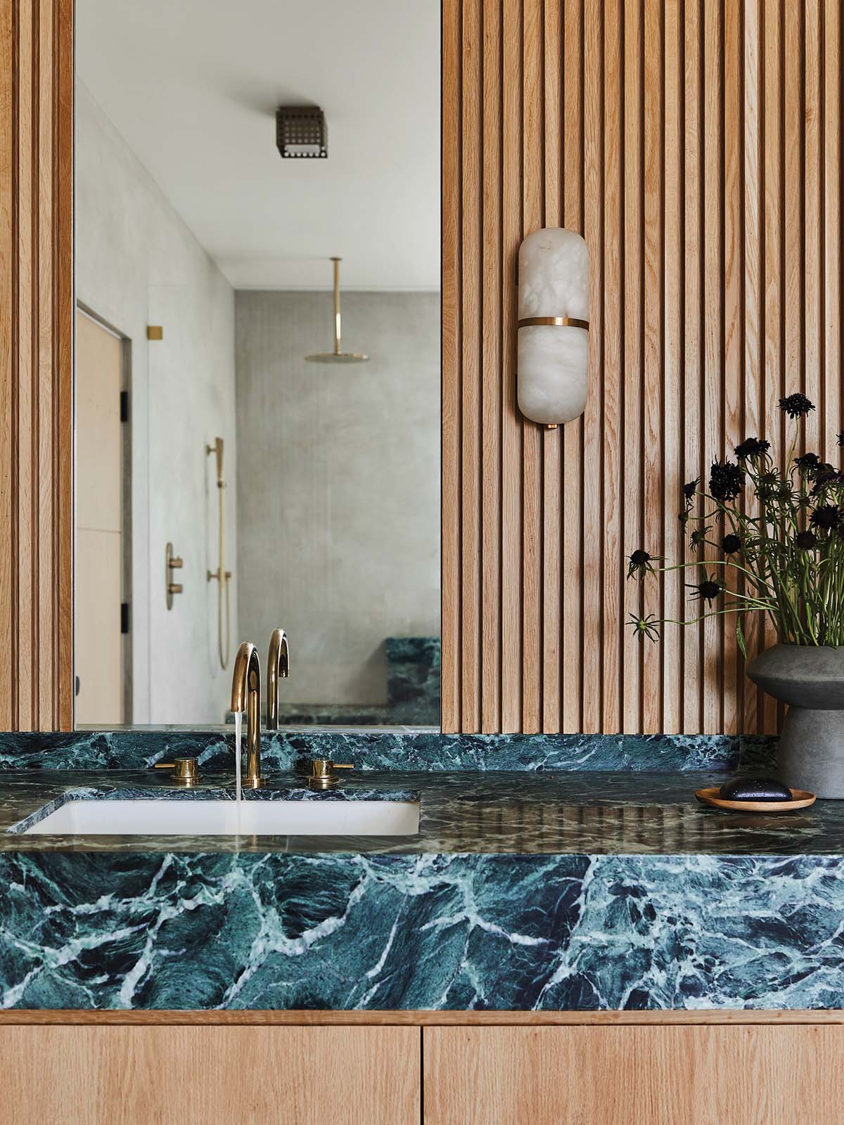 Wood panelled bathroom with blue walls and wall lighting. This is how you create stylish bathrooms.