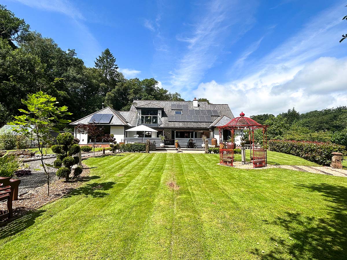 Scotland's Home of the Year episode 5. The exterior of the house is photographer by Kirsty Anderson, showing the secluded, homely back garden. Features include Alice in Wonderland trees, winding stone paths and wooden benches.