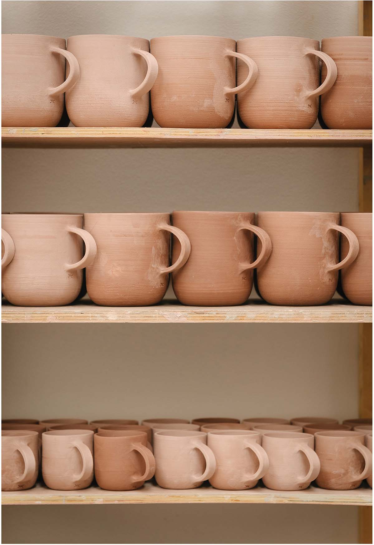 Cara Guthrie's shelf of ceramic mugs, formed and ready to design for her collaboration with IMAGE | Murray Orr. Ceramic mugs in Cara's studio, ready to be designed in collaboration with KESTIN®