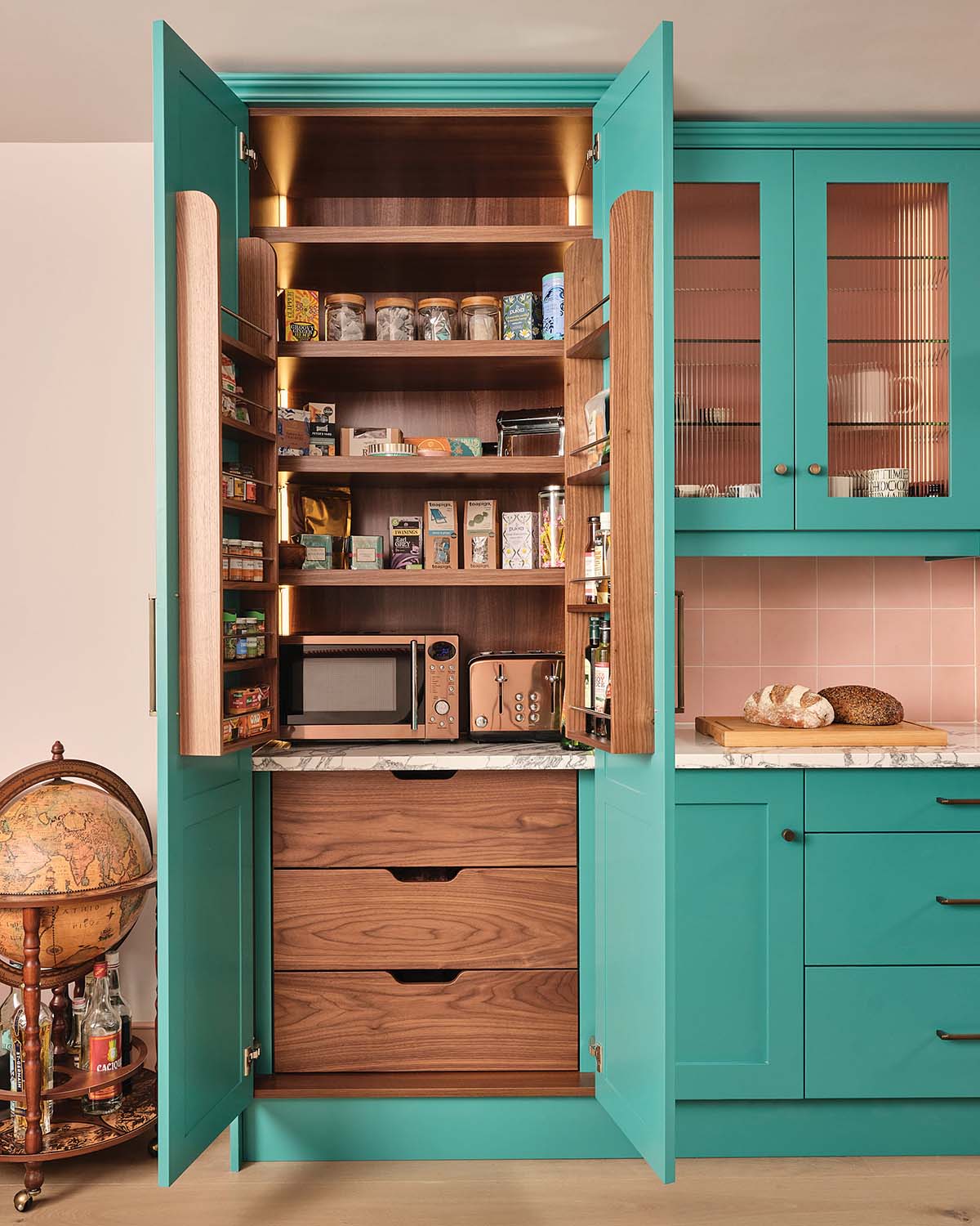 Countertops are grey and white marble, acting as a delightful break between a mostly blue, peach and black kitchen