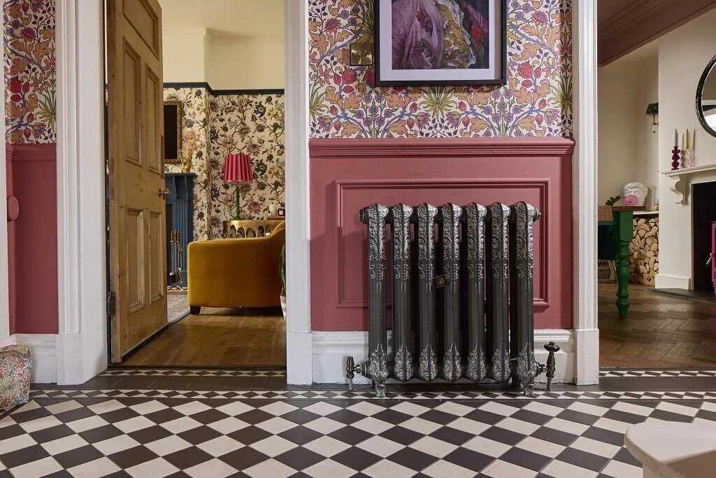 Cast iron radiator in hallway with black and white checked flooring and pink floral wallpaper