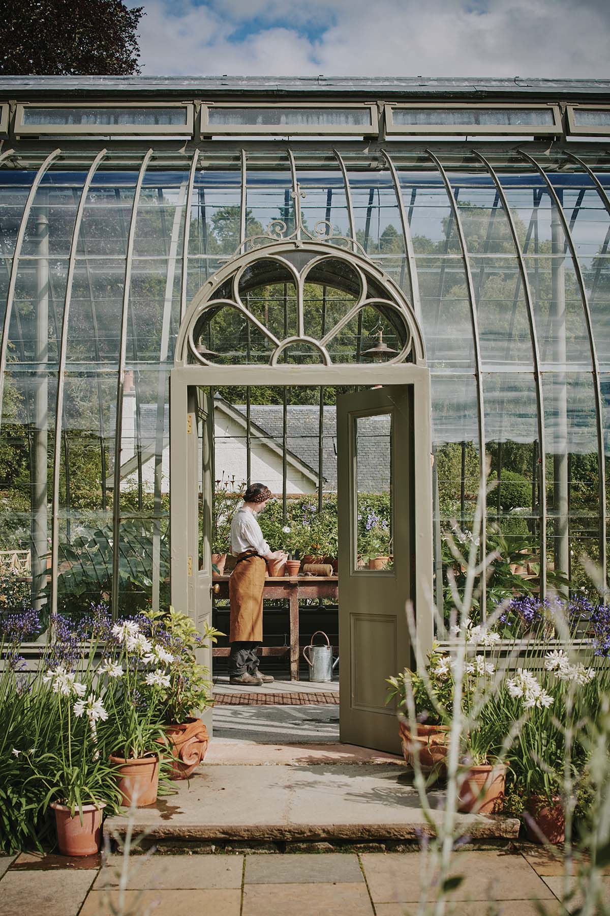 Gardener in large greenhouse on the ground of traditional Scottish property near Loch Ness