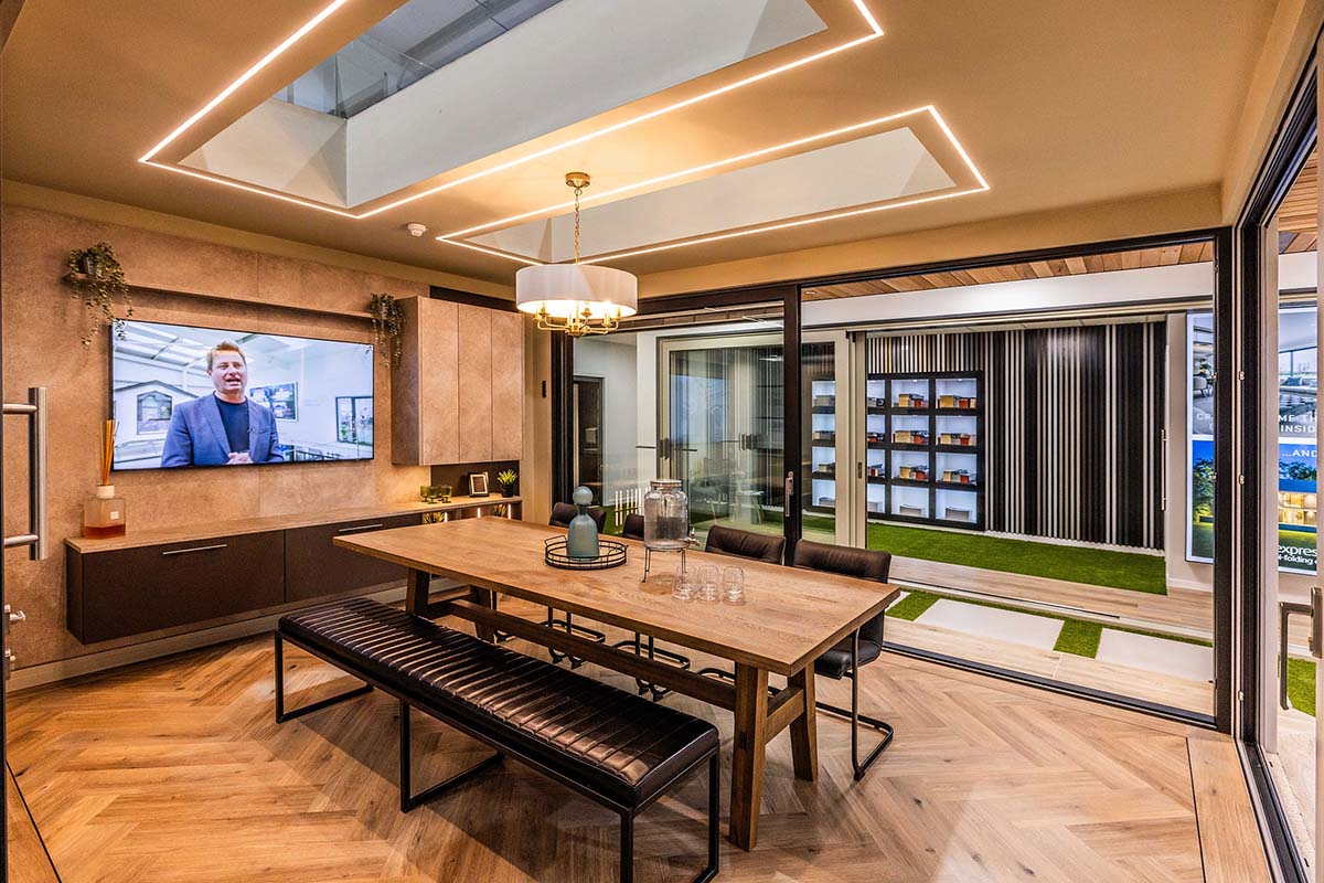 dining and living room area with wooden flooring, long brown and black dining table and wide screen TV