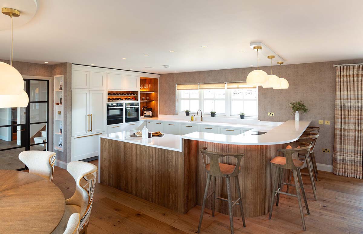 grand kitchen in traditional home in Scotland with hardwood paneling and floors as well as white cabinetry and subtle orange lighting for warmth