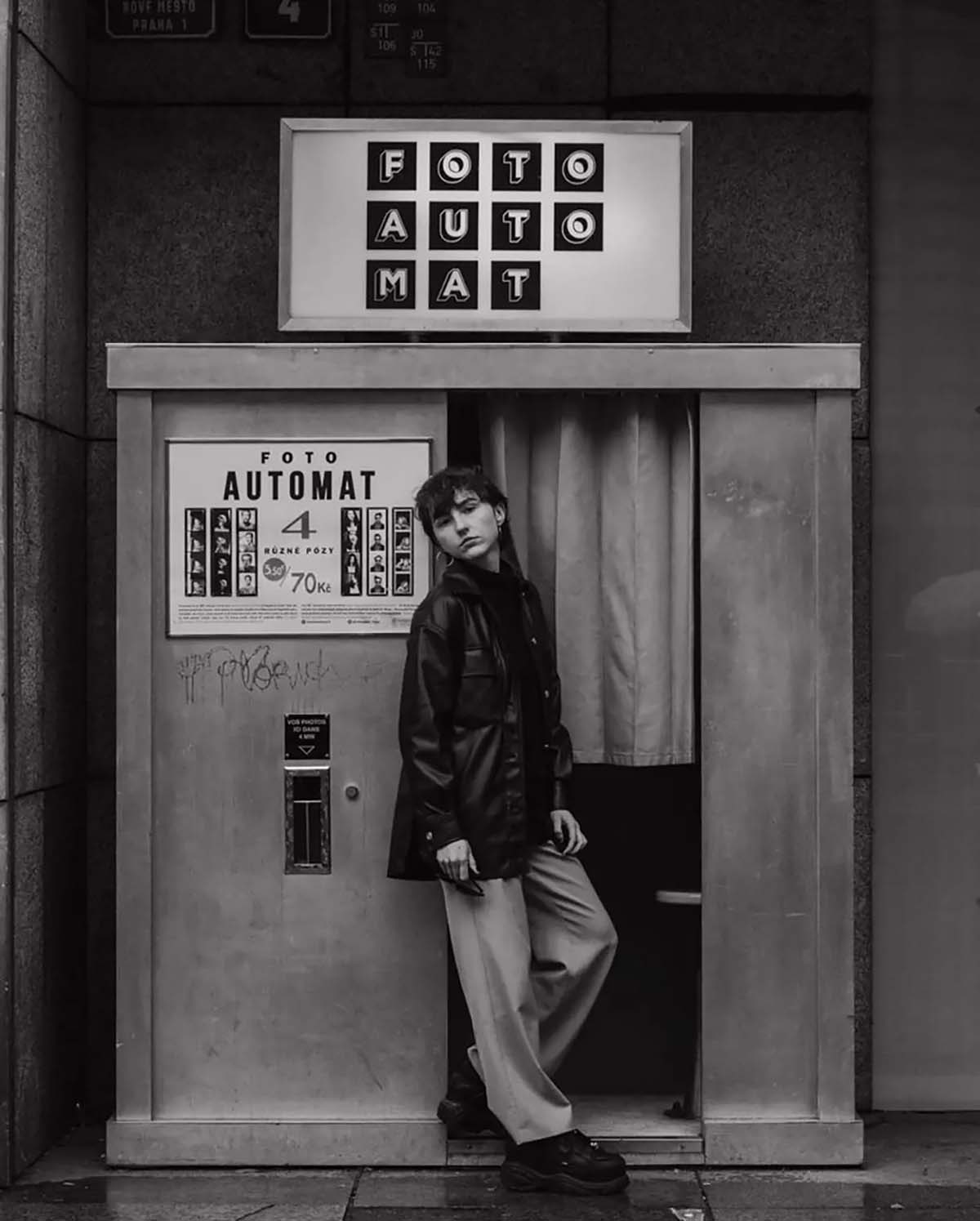 analogue photobooth with woman standing outside waiting for her photos to develop