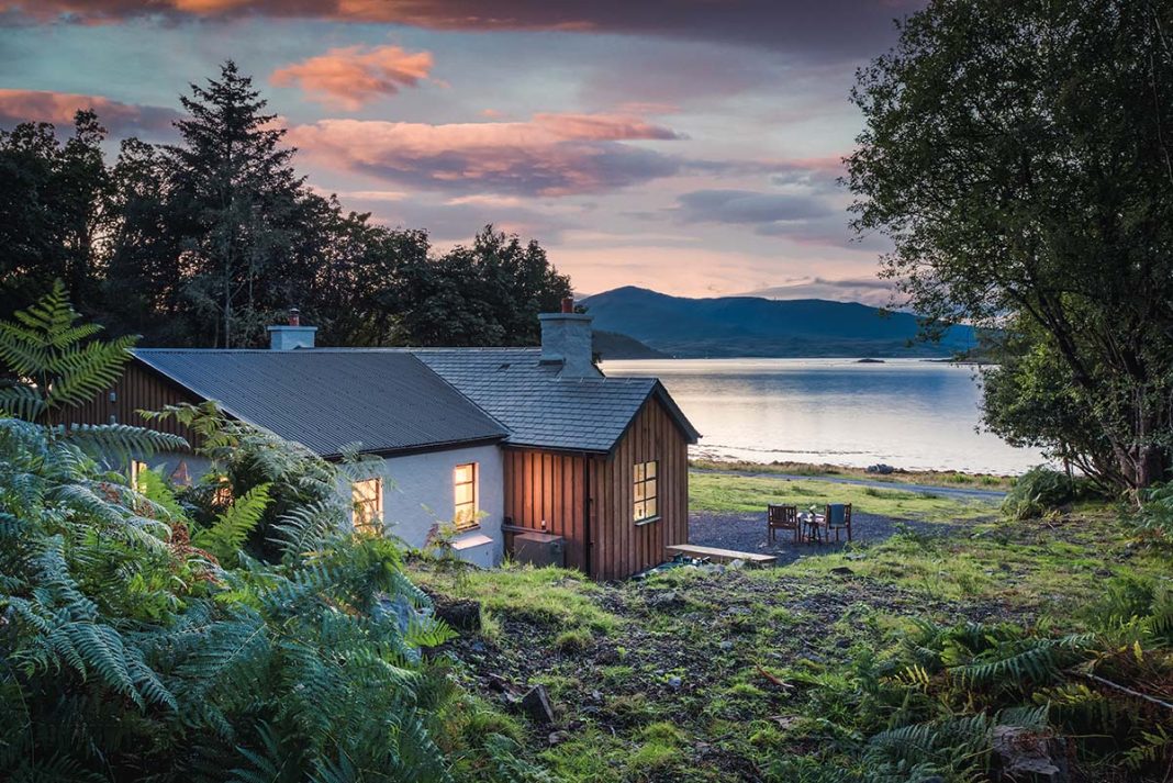 fern cottage on the isle of mull in scotland - exterior shot with the view of the scottish sea behind it