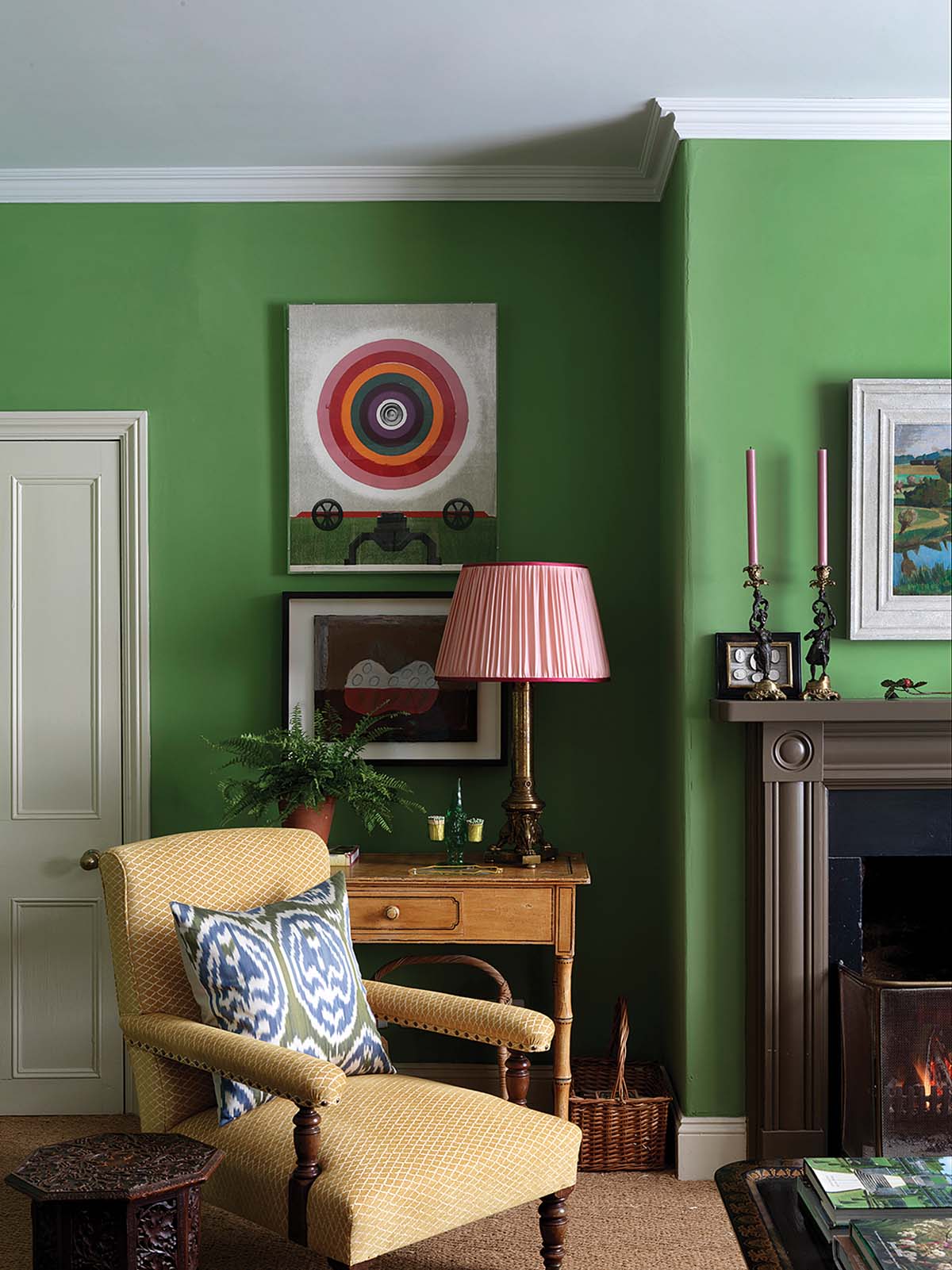 vibrant green living room with stone fire surrounds painted in black, offset by patterned sofas