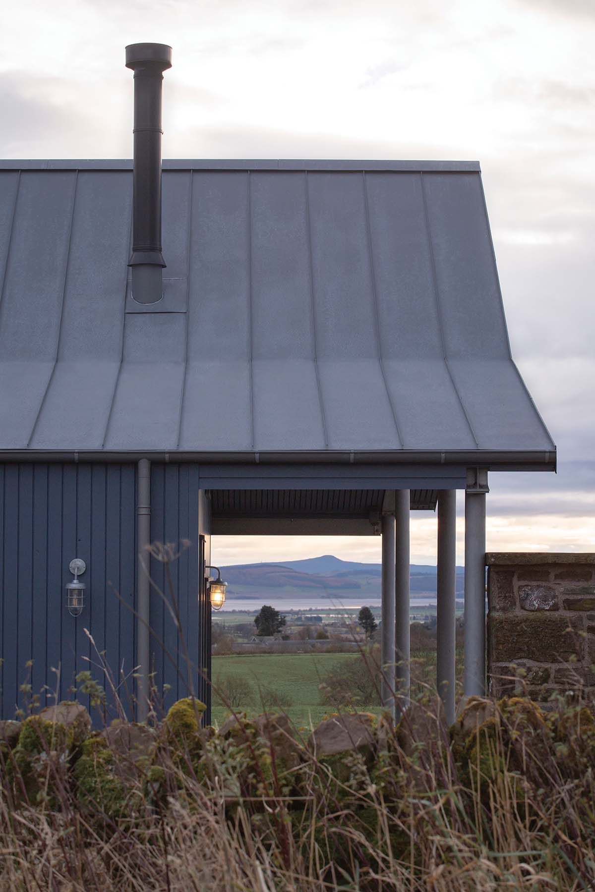 cool American barn-like roof on a house in scotland, surrounded by a loch